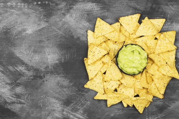 Tradiční latinskoamerické omáčkou guacamole v misce a nachos na tmavém pozadí. Pohled shora, kopírovat prostor. Jídlo pozadí — Stock fotografie