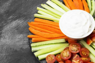 Kremalı sos beyaz kase ve karanlık bir arka plan üzerinde çeşitli sebze (domates, bir kereviz, salatalık, havuç). Uzay kopyalayın. Gıda arka plan.