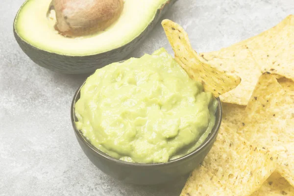 Molho latino-americano tradicional guacamole em uma tigela e nachos. Tonificação . — Fotografia de Stock