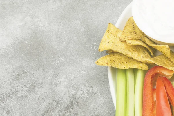 Molho cremoso em tigela branca, vários legumes (aipo, pimenta) e nachos. Vista superior, espaço de cópia. Fundo alimentar. Tonificação — Fotografia de Stock