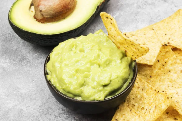 Molho latino-americano tradicional guacamole em uma tigela e nachos . — Fotografia de Stock