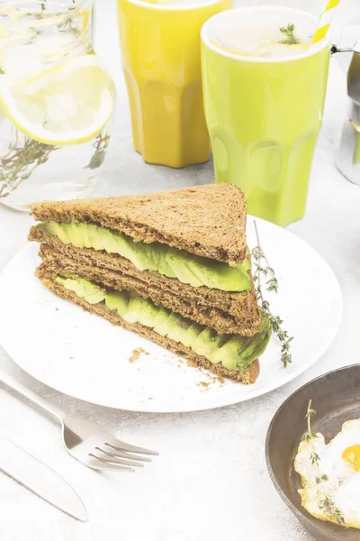 Café da manhã - um brinde de pão de centeio com abacate, ovos fritos, limonada e café em um contexto leve. Tonificação — Fotografia de Stock