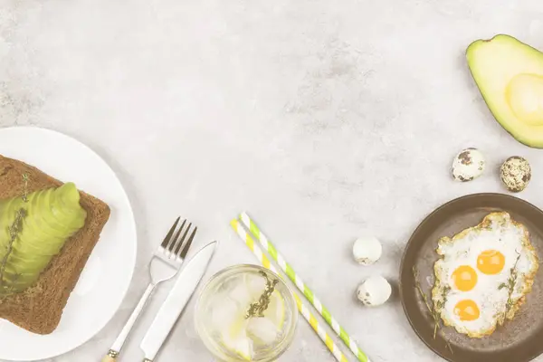 전통적인 아침 식사-토스트와 아보카도, 메 추 라 기 계란에서 튀긴된 계란, 밝은 배경에 레모네이드 호 밀 빵에서. 보기 상위, 공간을 복사 합니다. 음식 배경입니다. 토닝 — 스톡 사진
