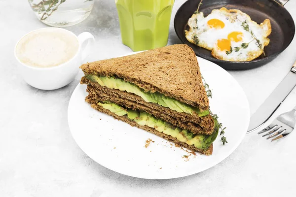 Завтрак - тост из ржаного хлеба с авокадо, жареные яйца, лимонад и кофе на светлом фоне — стоковое фото