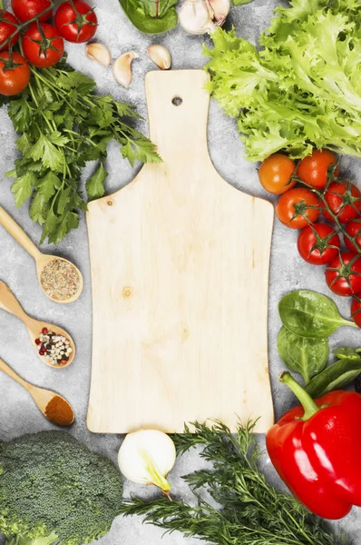 Surtido de verduras frescas (pimienta, tomates cherry, cebollas, ajo, espinacas, brócoli) y especias sobre un fondo claro. Tabla de cortar de madera. Vista superior, espacio de copia. Fondo alimentario — Foto de Stock