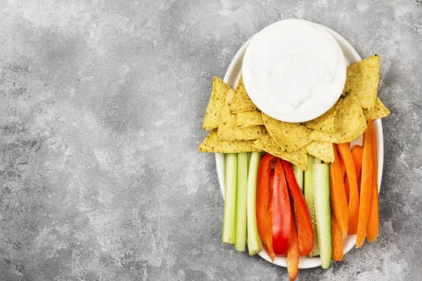 Molho cremoso em tigela branca, vários legumes (aipo, pimenta) e nachos. Vista superior, espaço de cópia. Fundo alimentar — Fotografia de Stock