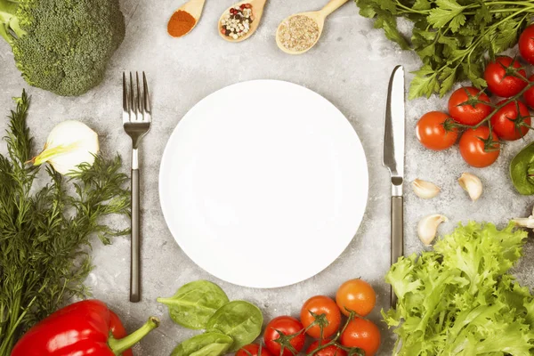 Concepto de alimentos dietéticos y vegetales. Placa blanca. Varias verduras y especias (brócoli, pimienta, tomates cherry, ajo, lechuga, perejil, hinojo) sobre un fondo claro. Vista superior, espacio de copia. Fondo alimenticio. Tonificación — Foto de Stock