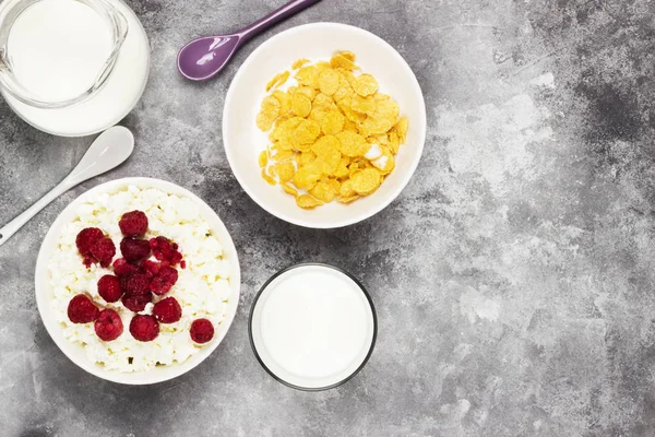 Cottage cheese in bowl with frozen raspberry and cup of cornflak