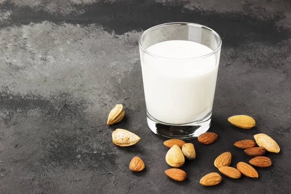 Vegan almond milk in glass on a dark background. Non-dairy milk.