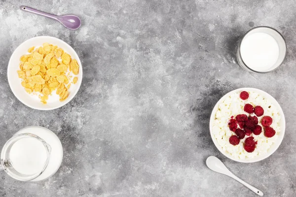 Cottage cheese in bowl with frozen raspberry and cup of cornflak