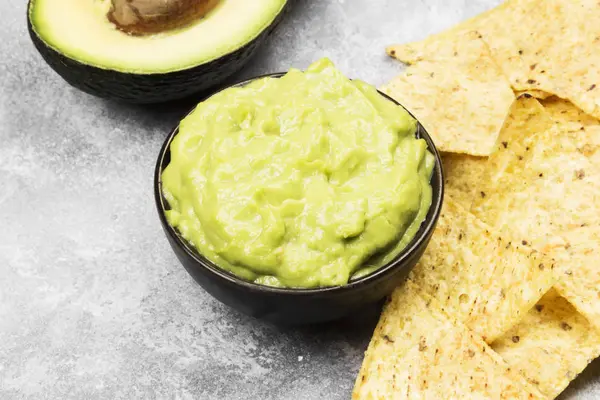 Molho latino-americano tradicional guacamole em uma tigela e nachos — Fotografia de Stock