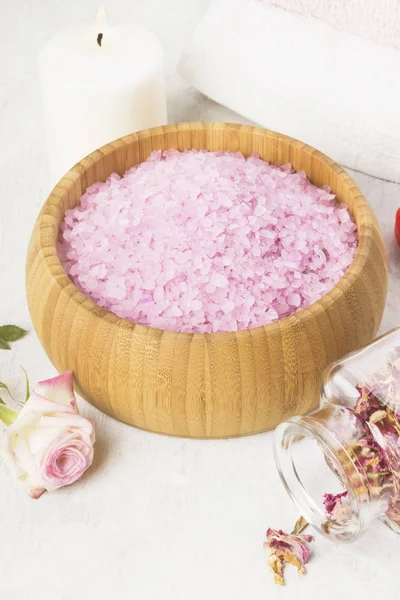Sal de baño con aroma a rosa en un cuenco de madera, pétalos y rosa fresca, toallas y velas sobre fondo blanco. Tonificación — Foto de Stock