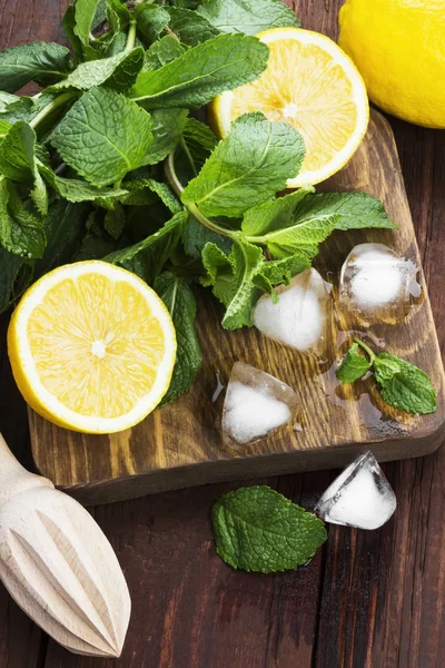 Ingredients for lemonade - lemon, mint, ice on a wooden cutting — Stock Photo, Image