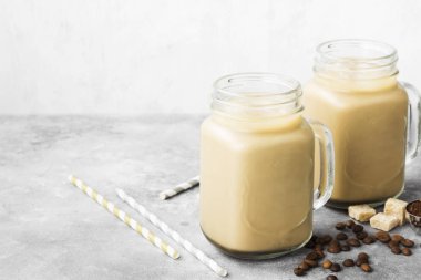 Buz gri bir arka plan üzerinde uzun bir bardak sütlü kahve. Uzay kopyalayın. Gıda arka plan