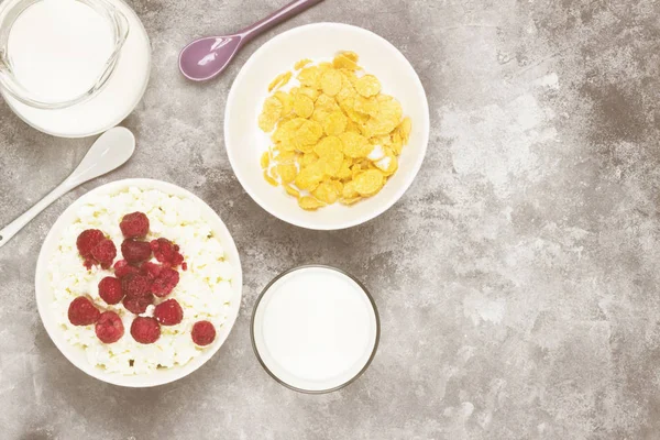 Cottage cheese in bowl with frozen raspberry and cup of cornflak