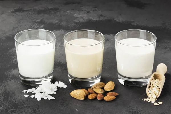 Vegan oat, almond, coconut milk in glass on a dark background. Non-dairy milk