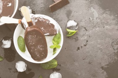 Vanilyalı dondurma çubuk üzerinde karanlık bir arka plan üzerinde çikolata sır ile kaplı. Görünümü en çok, uzay kopyalayın. Gıda arka plan. Tonlama