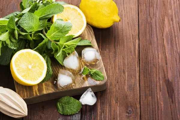 Ingredients for lemonade - lemon, mint, ice on a wooden cutting — Stock Photo, Image