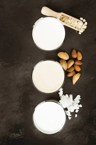 Avena vegana, mandorla, latte di cocco in vetro su fondo scuro. N — Foto Stock