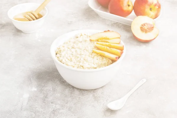 Oatmeal with nectarine and honey on a gray background. Toning — Stock Photo, Image