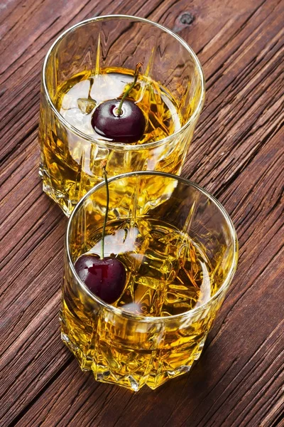 Cocktail från whisky med körsbär i två glas på en trä rygg — Stockfoto