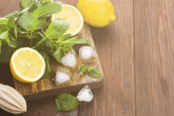 Los ingredientes para la limonada - el limón, la menta, el hielo sobre el corte de madera — Foto de Stock