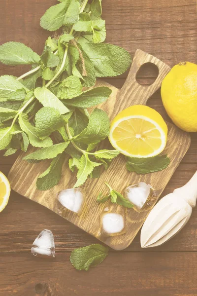 Los ingredientes para la limonada - el limón, la menta, el hielo sobre el corte de madera — Foto de Stock