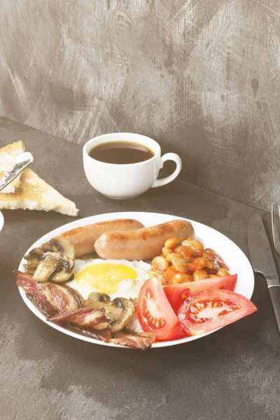 Традиционный английский завтрак - бекон, сосиски, яичница, том — стоковое фото