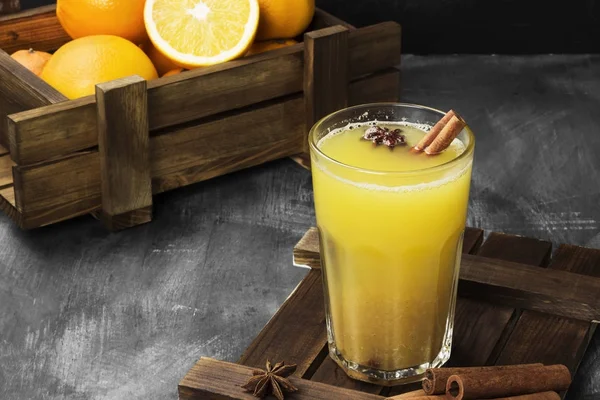 Зимний горячий напиток из апельсинов и специй на черном фоне . — стоковое фото