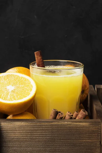 Winter hot drink from oranges and spices on a black background — Stock Photo, Image