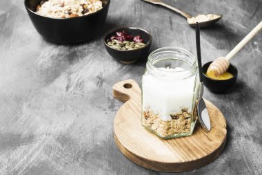 Granola yoğurt, bal, fındık, meyve karanlık bir arka plan ile. Co