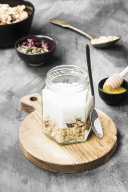 Granola ile yoğurt, bal, fındık, meyve karanlık bir arka plan üzerinde