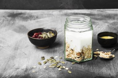 Granola yoğurt, bal, fındık, meyve karanlık bir arka plan ile. Co