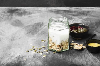 Granola yoğurt, bal, fındık, meyve karanlık bir arka plan ile. Co