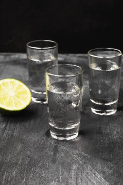 Siyah arka planda shot bardaklarında soğuk votka.