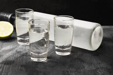 Siyah arka planda shot bardaklarında soğuk votka.