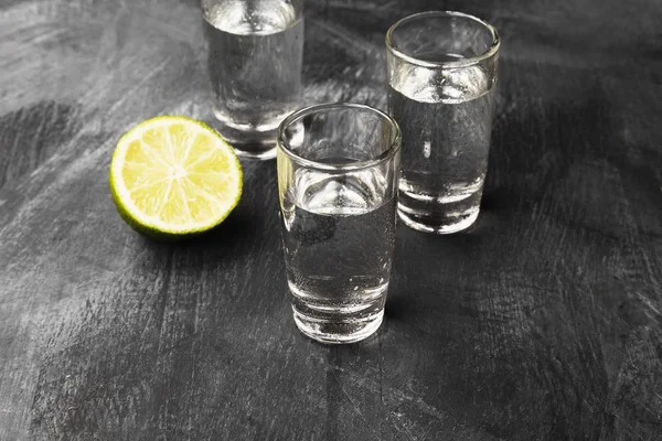 Kall vodka i shotglasögon på en svart bakgrund — Stockfoto