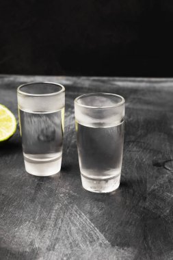 Siyah arka planda shot bardaklarında soğuk votka.