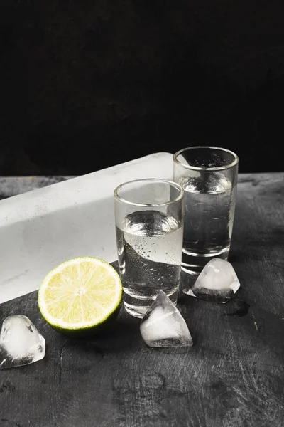 Vodka frío en vasos de chupito sobre fondo negro — Foto de Stock