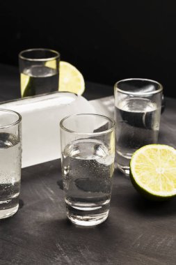 Siyah arka planda shot bardaklarında soğuk votka.