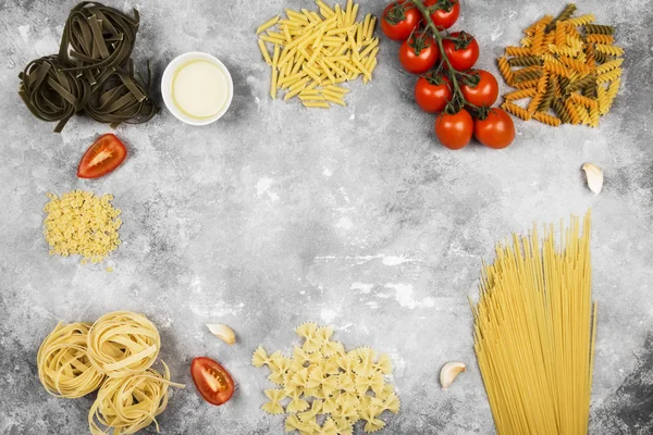 Various raw pasta and ingredients for cooking (tomatoes, olive o