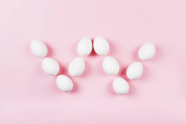 White eggs in form of letter "w" on pink background. Concept gen — Stock Photo, Image