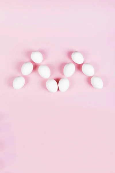 White eggs in form of letter "m" on pink background. Concept gen — Stock Photo, Image