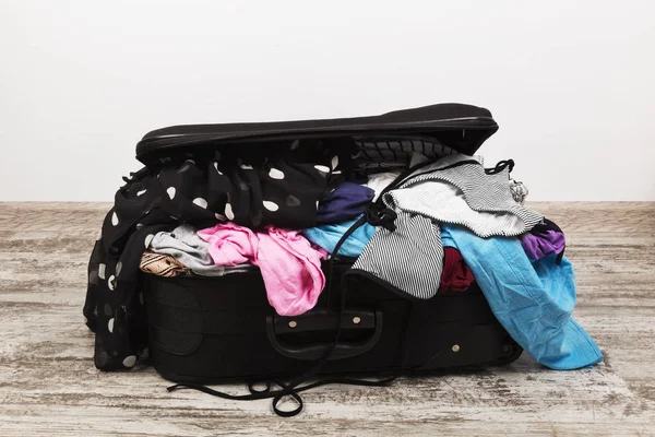 Embalagem descuidada de roupas em mala preta — Fotografia de Stock