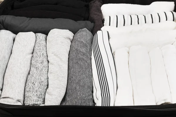 Embalaje de ropa monocromática en maleta negra — Foto de Stock
