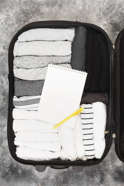 Emballage de vêtements monochromes dans une valise noire. Liste d'emballage dans — Photo