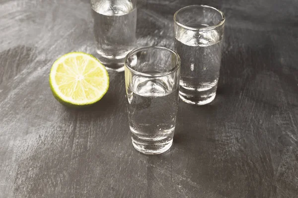 Vodka fria em copos de tiro em um fundo preto. Tonificado — Fotografia de Stock