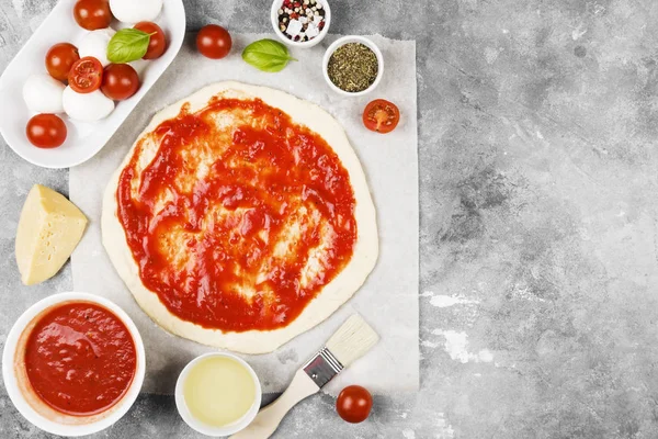 Pasta per pizza e ingredienti per pizza su sfondo grigio. Superiore vi — Foto Stock