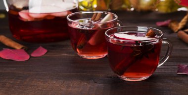 Elmalı kırmızı çay, elmalı, tarçınlı sıcak içecek ve cam çaydanlıkta anason ve ahşap zemin üzerinde iki bardak. Boşluğu kopyala