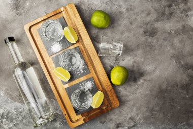 Tekila şişesi, shot, limon, ahşap tahtada tuz. Üst görünüm, alanı kopyala